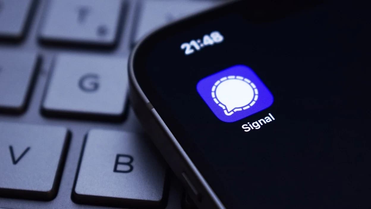 Karanlık masaüstü klavye üzerinde gece ışığında iPhone ekranında Signal uygulaması simgesi